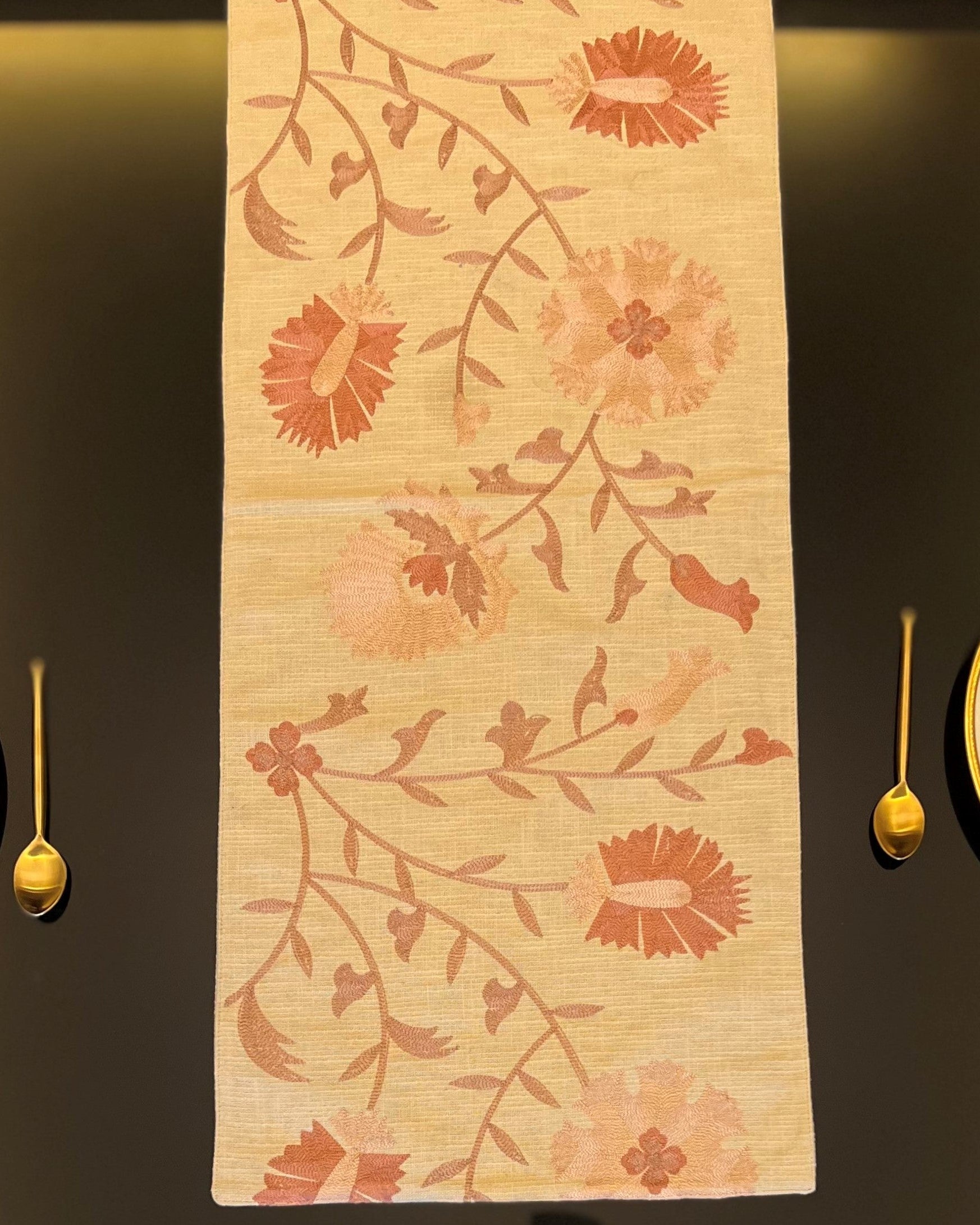 A beige table runner with a floral pattern